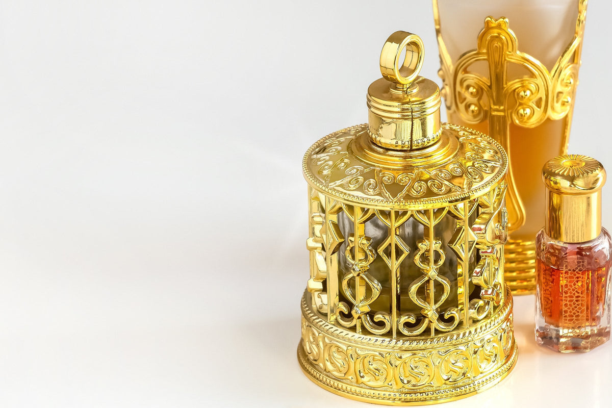An ornate golden flask of oud perfume oil on a white background