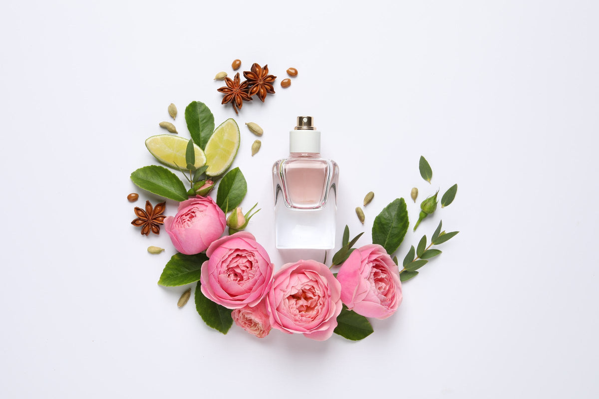 A perfume bottle with lime and fresh flowers on a white background