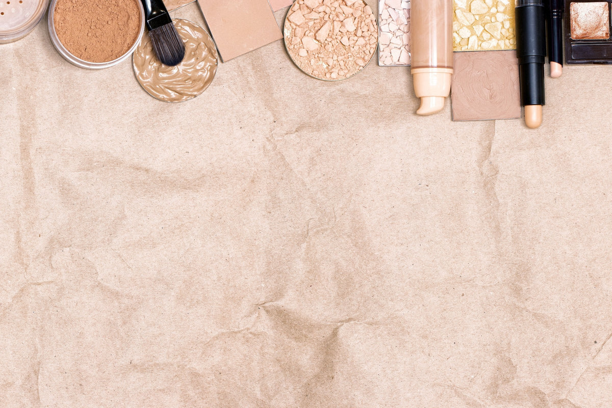 Primer, concealer, foundation and face powder laid out on craft paper