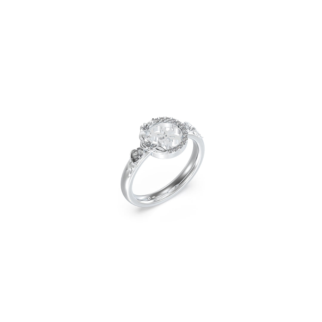 Silver engraved floral ring with circular stone-studded centerpiece on neutral background