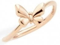 Rose gold openwork butterfly ring on neutral surface, delicate feminine design, close-up showing polished finish